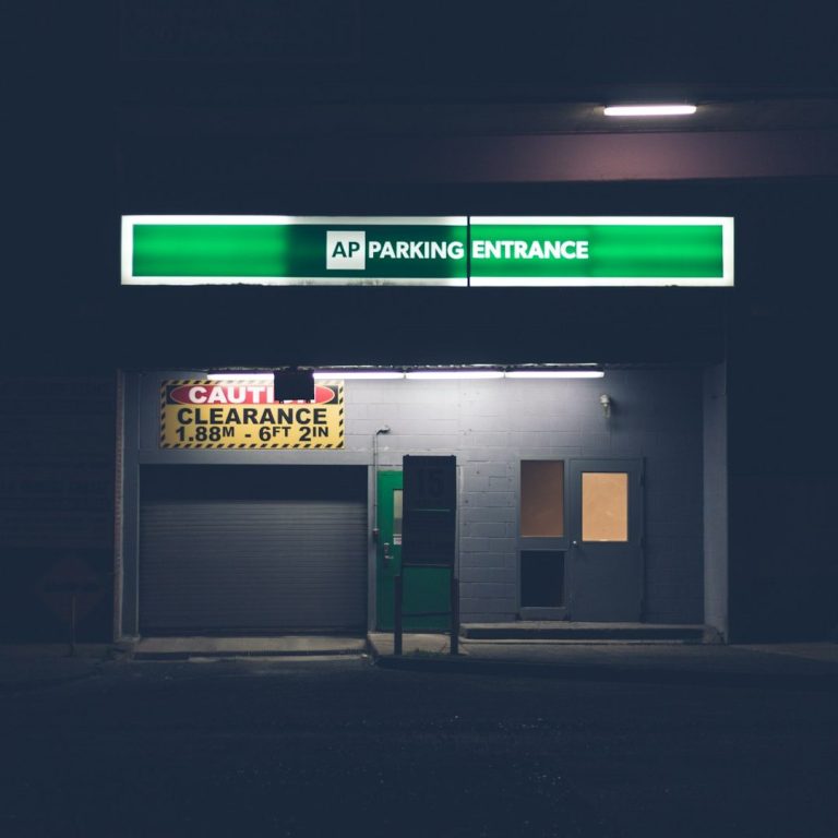 Beleuchtete Tankstelle mit abgedunkeltem Umfeld, Anzeigen in Neonfarbe.